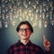 Joyful guy pointing index finger up, showing multiple light bulbs as creative ideas isolated on grey wall background. Positive