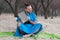 Joyful handsome bearded man in blue kimono sitting, swinging with book, laughing and looking away