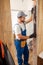 Joyful handyman, male worker in uniform using spirit level while checking wall measurements indoors