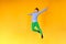 Joyful and happy boy expresses his emotions in a jump, a child is jumping on a yellow background