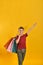 A joyful and happy buyer with colored bags in his hand shows his positive emotions from purchases. Baby with purchases on a yellow