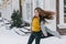 Joyful happy girl enjoying snowing weather on steet. Fashionable young woman with long brunette hair walking in snowfall