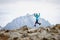 Joyful happy traveler woman jumping over stones on the background of a high mountain