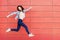 Joyful happy young woman jumping against red wall. Excited beautiful girl portrait