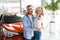 Joyful husband and wife in a car dealership.