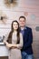 Joyful husband and wife posing by the decorative fireplace. Festive clothes and decorations