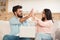 Joyful indian couple using laptop and giving high-five celebrating success or great news, sitting on sofa at home