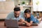 Joyful indian father with son watching laptop by lying on floor at home - concept of cyberspace, Joyful Bonding and