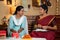 Joyful indian mother with daughter preparing of diwali festival celebration by packing gifts and stringing lowers at