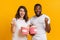 Joyful interracial couple cheering with popcorn buckets, raising fists in excitement