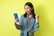 Joyful Japanese Female Using Smartphones Gesturing Yes Over Yellow Background