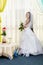 A joyful Jewish bride with her face covered with a veil and a bouquet of white roses is standing in the synagogue before