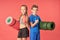 Joyful kids with sports equipment standing against red background