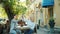 Joyful ladies chatting then doing high-five in outdoor cafe in city street