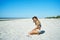 Joyful latin girl sitting on white sand at serene secluded seashore. This delightful moment joy and freedom