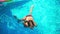 Joyful laughing Caucasian girl having fun swimming with kiwi toy in blue water in swimming pool. Portrait of cheerful