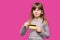Joyful little blonde shy face girl 6-7 years old hold credit bank card isolated on pink. Childhood lifestyle concept