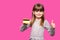 Joyful little blonde shy face girl 6-7 years old hold credit bank card with thumb up isolated on pink. Childhood lifestyle concept