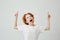 Joyful little boy with curly ginger hair and freckles isolated on white background, pointing upside with happy silly