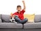 Joyful little boy sitting on a sofa and playing a soccer video game