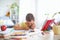 Joyful little boy sitting at the table with pencils and textbooks. Happy child pupil doing homework at the table. improper posture