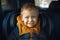 A joyful little boy smiles in a child`s car seat. Child safety when driving