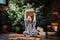 Joyful little girl with blonde curly hair wearing a warm sweater throws up a gift box while sitting on a floor next to