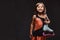 Joyful little girl dressed in skater dress holds ice skates. Isolated on a dark textured background.