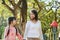 Joyful little girl and grandmother walking in park surrounded by green trees at sunlight morning. Family, generation