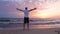 Joyful man rising up hands enjoying morning sunset at sea beach