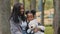 Joyful mom and daughter sitting on bench in park young mother hugs child shy little girl holding teddy bear african