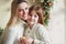 Joyful mother and lovely girl daughter in cozy knitted sweaters decorating Christmasmas fir tree with new year bauble