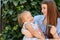 Joyful older sister holding younger sister, playing and laughing, having fun. Teen girl holding baby girl on summer day