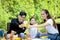 Joyful parent and kid child make barbecue at picnic party, have fun together in summer green garden, father mother and daughter