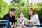 Joyful parent and kid child make barbecue at picnic party, have fun together in summer green garden, father mother and daughter