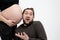 Joyful, playful happy bearded man in casual clothes is listening with funny face to his pregnant wife`s tummy, isolated