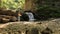 Joyful playful little girl throwing pebbles in mountain river on background green forest. Concept of active recreation