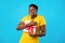 Joyful Plus-Size Black Woman Hugging Gift Box Over Blue Background