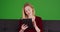 Joyful portrait of young millennial woman sitting on sofa on green screen