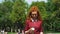 Joyful red haired girl walking in green park on sunny day