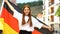 Joyful red-haired teen waving German flag and smiling on camera, patriotism