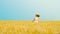 Joyful red haired woman in white dress jumping in wheat field in slow motion