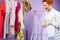 Joyful redhead woman chose for her violet sundress on hanger holding in her hand and looking at it with love.