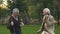 Joyful retired men dancing park with walking sticks, having fun together, humor