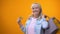 Joyful retiree lady showing shopping bags and golden card, standing customer