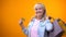 Joyful retiree lady showing shopping bags and golden card, standing customer