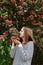 Joyful satisfied caucasian woman dressed striped shirt posing blooming tree in park in early spring nature enjoying pleasant