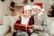 Joyful senior couple sitting and holding a gift.