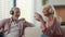 Joyful senior elderly Caucasian married couple grandparents man woman listening music using headphones dancing fooling
