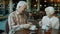 Joyful senior man and woman having fun talking laughing doing high-five at table in restaurant